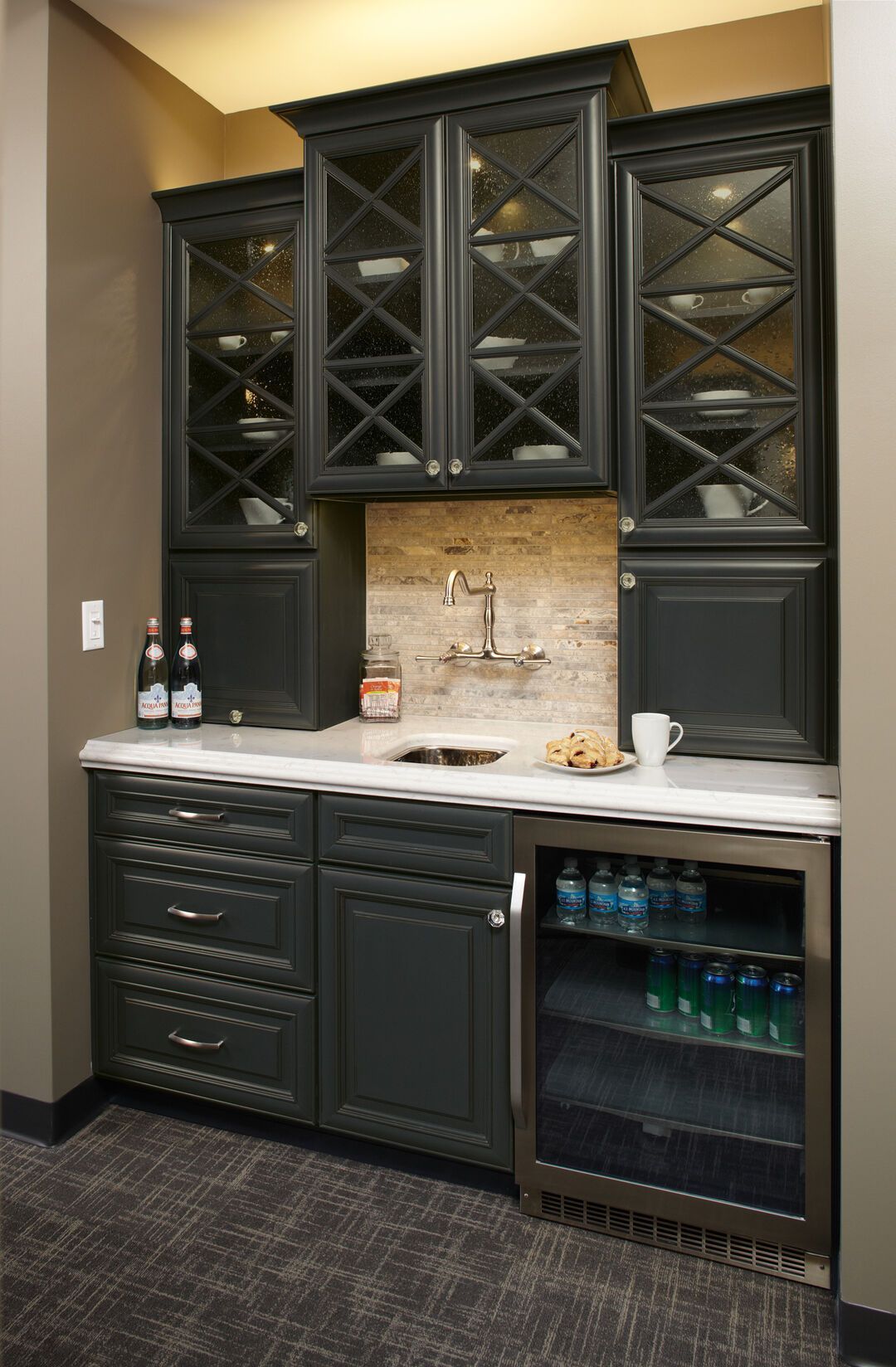 Butler pantry with dark green glass-front cabinetry, stone backsplash and a beverage fridge