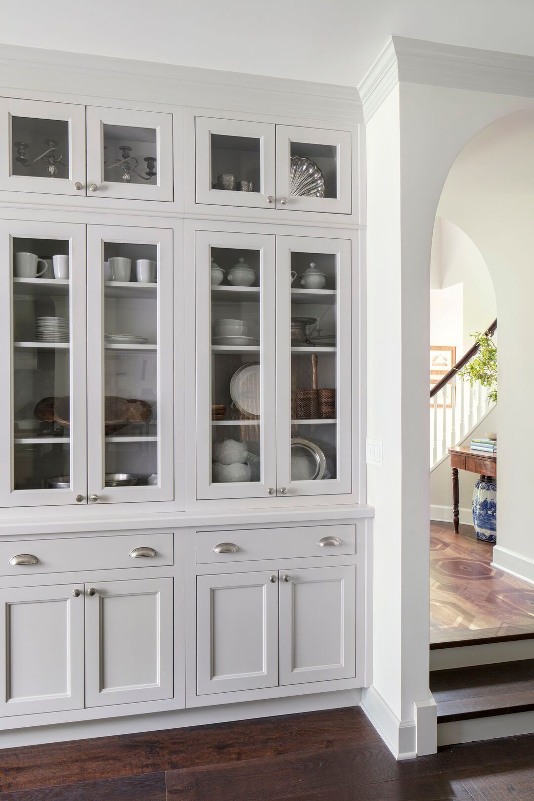 Custom built-in cabinetry with glass-front upper doors and cup-pull drawers