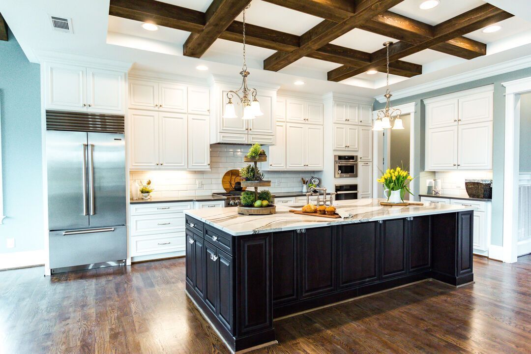 Open remodeled kitchen with white cabinetry, a dark island and exposed ceiling beams