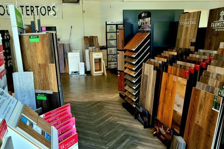 Hardwood and luxury vinyl plank flooring samples displayed on racks in the ProLux Remodeling showroom